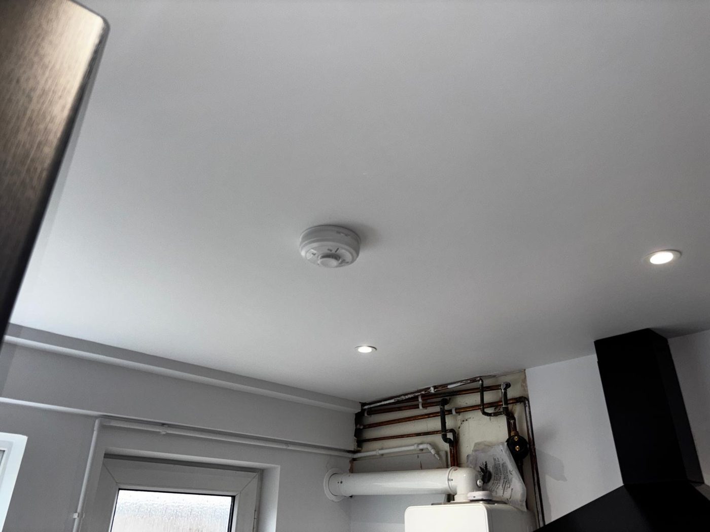 A kitchen ceiling with a heat alarm and downlights
